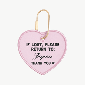 Pink heart-shaped tag with text 'If lost, please return to: Japan' on a white background