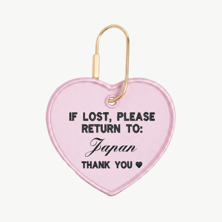 Pink heart-shaped tag with text 'If lost, please return to: Japan' on a white background
