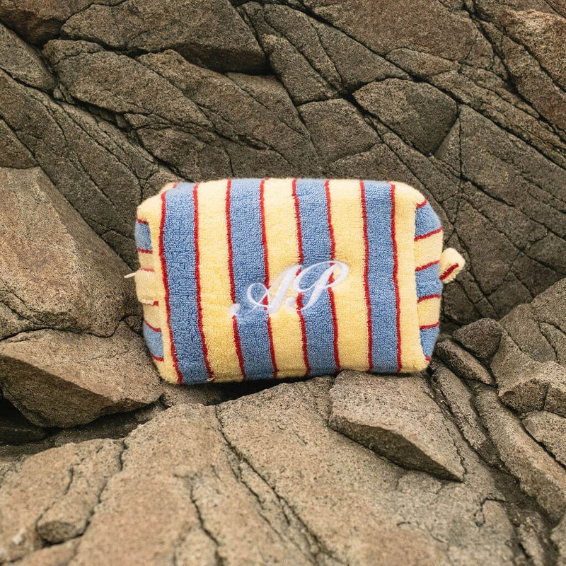 Colorful striped pouch on a stone bench with ocean in the background