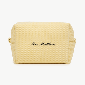 A cream-colored waffle pouch with the text 'Mrs. Matthews'  on the front, displayed on a plain white background.