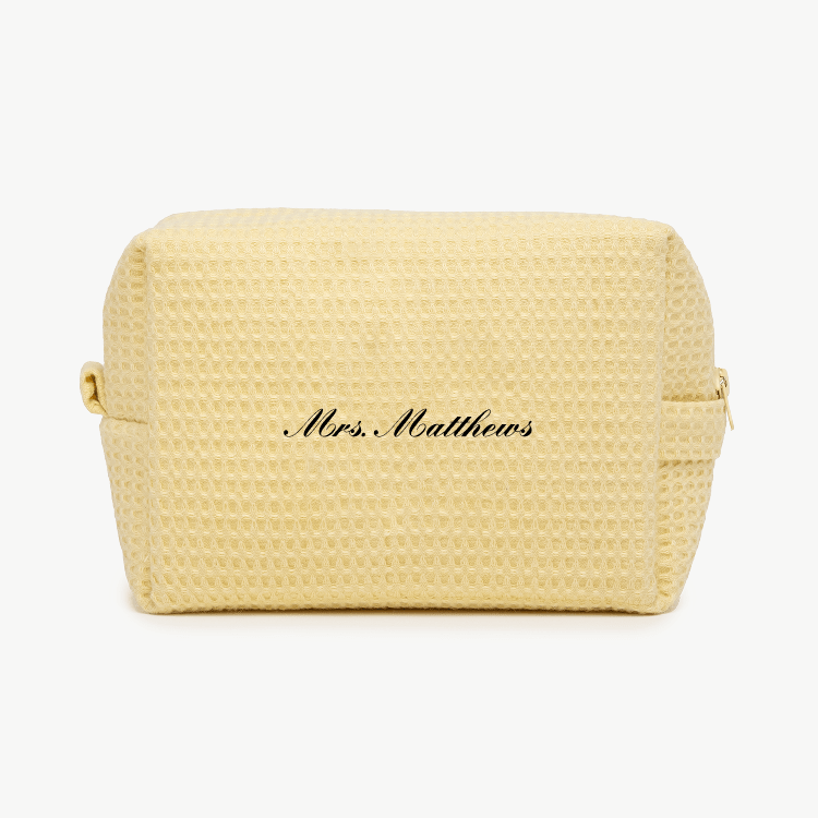 A cream-colored waffle pouch with the text 'Mrs. Matthews'  on the front, displayed on a plain white background.