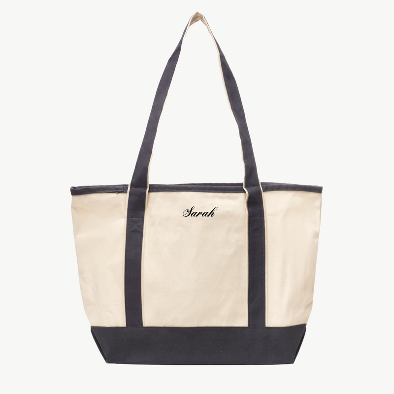 A beige canvas tote bag with long gray handles and a matching gray base. The name Sarah is embroidered in black on the front, displayed on a white background.