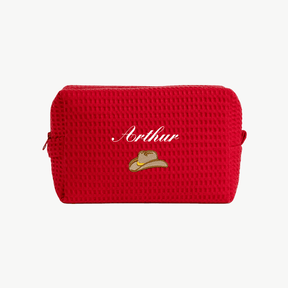 A red, waffle pouch with the name Arthur and a small embroidered cowboy hat below the name on the front.