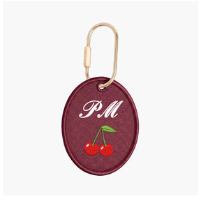 Maroon keychain with 'PM' and cherries on a white background
