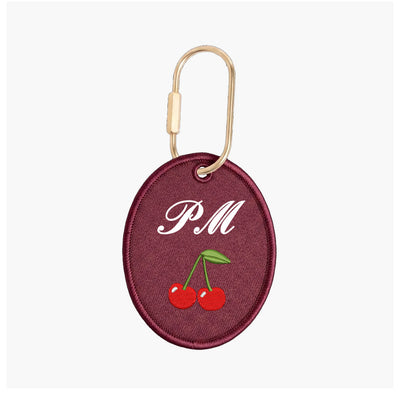 Maroon keychain with 'PM' and cherries on a white background
