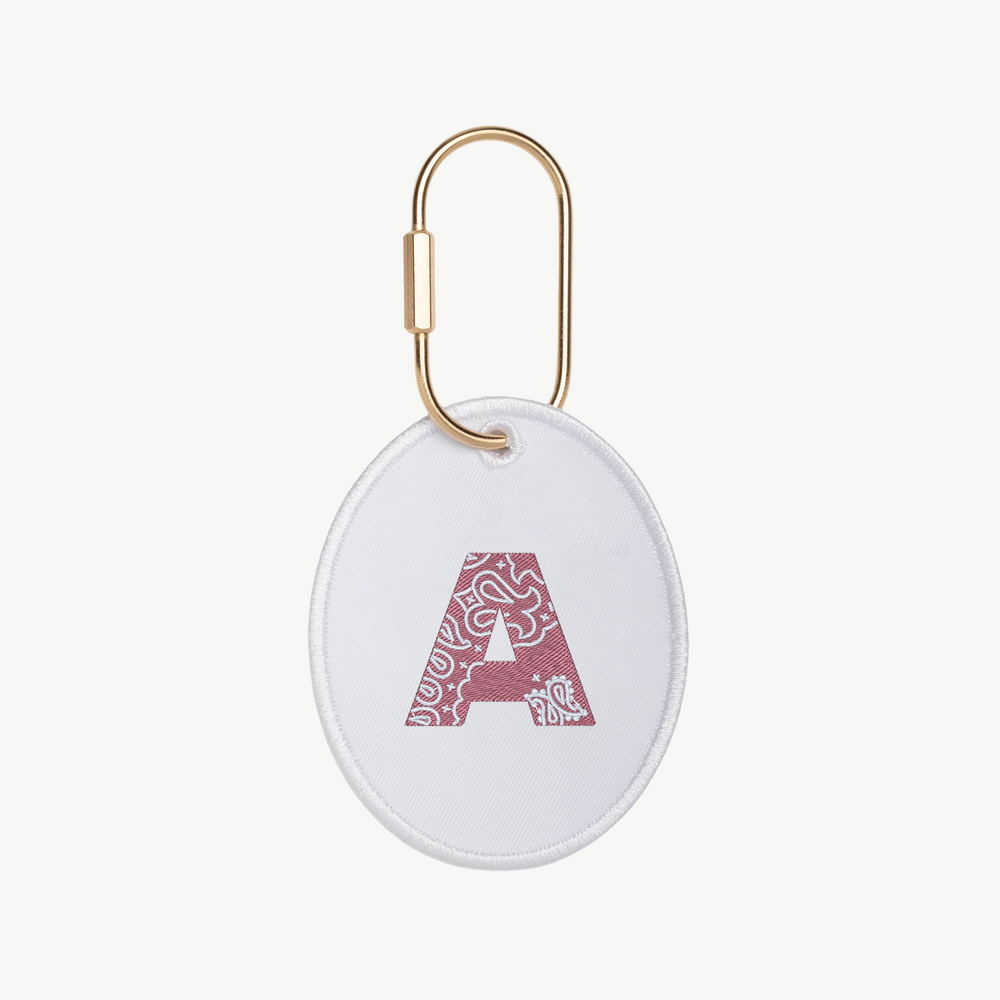 An oval-shaped charm keychain with an embroidered letter A with bandana design, on a white background
