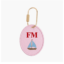 Pink oval keychain with sailboat design and 'FM' initials on a white background
