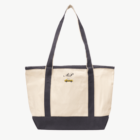 A beige canvas tote bag with long gray handles and a matching gray base, featuring  'AP' and a taxi icon embroidered on the front, displayed on a white background.