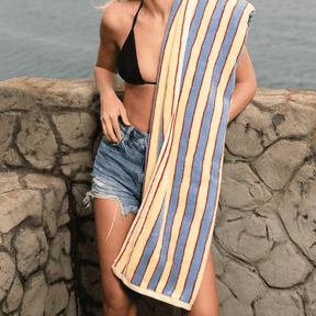 Woman holding a striped towel by the water