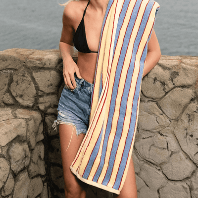 Woman holding a striped towel by the water