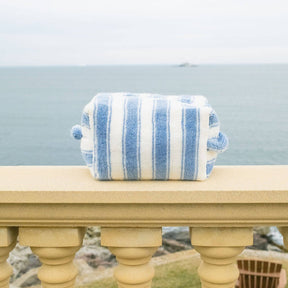 Blue and white striped pouch on a stone ledge with a scenic background