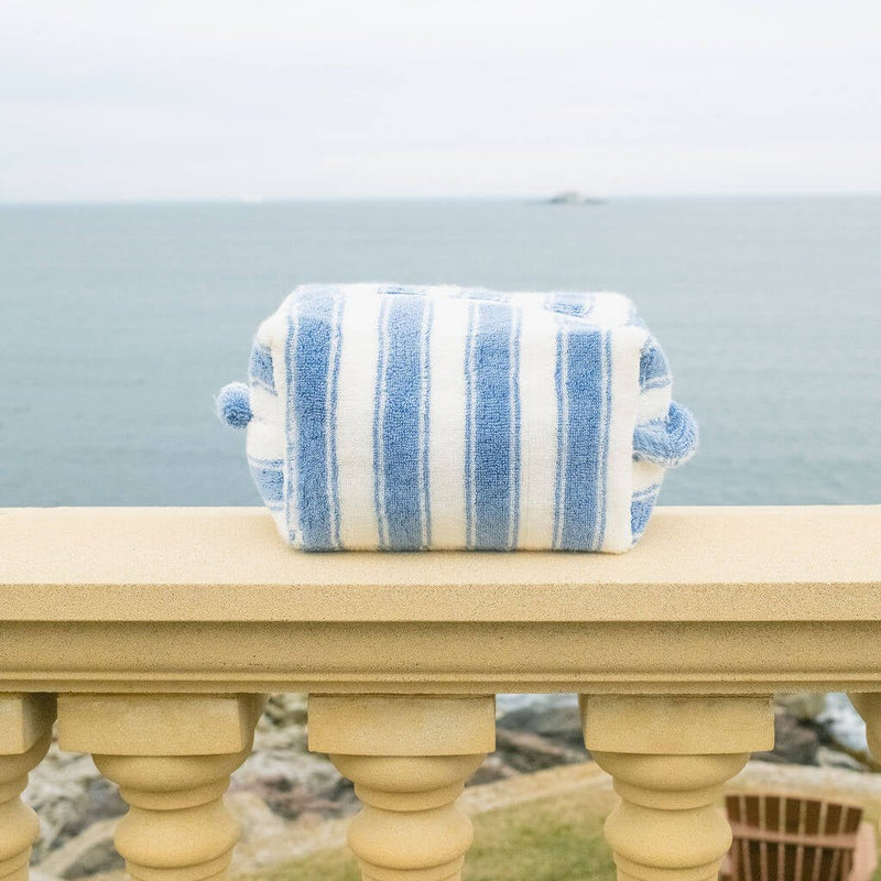 Blue and white striped pouch on a stone ledge with a scenic background