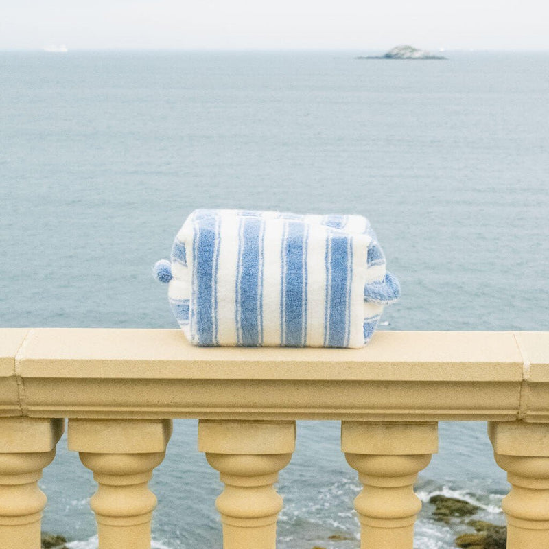 Blue and white striped pouch on a railing with ocean view
