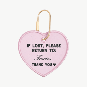 Pink heart-shaped keychain with text 'If lost, please return to: Texas' on a white background