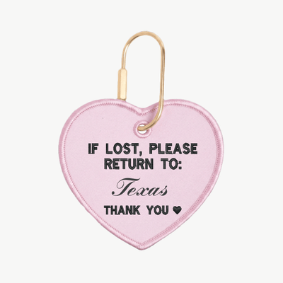 Pink heart-shaped keychain with text 'If lost, please return to: Texas' on a white background