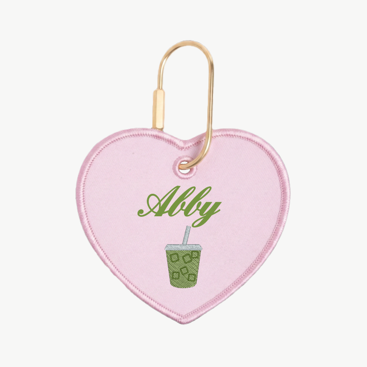 Heart-shaped keychain with 'Abby' and a green drink design on a white background