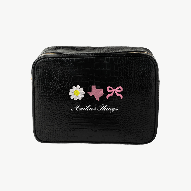 Black toiletry bag with decorative elements and 'Anikas Things' branding on a white background