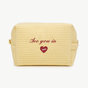 Yellow textured pouch with 'See you in Austin' text and heart design on a white background