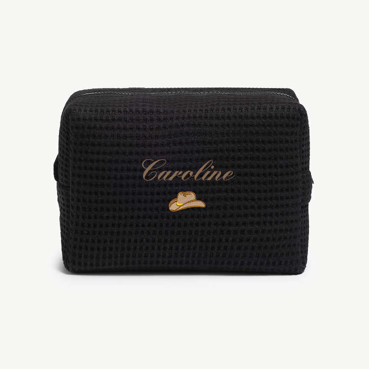 Black textured pouch with 'Caroline' and a hat emblem on a white background