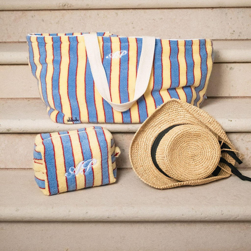 Striped beach bag and pouch with a straw hat on wooden steps