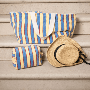 Striped beach bag and pouch with a straw hat on wooden steps