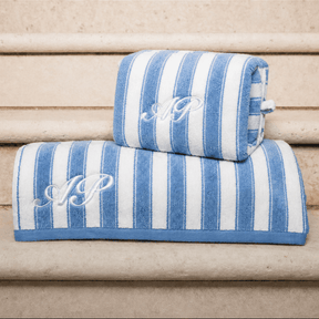 Blue and white striped towel and pouch with monogram on a wooden surface