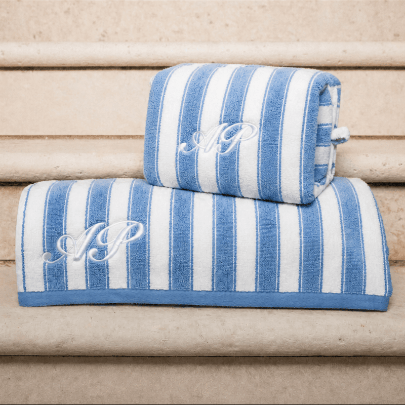 Blue and white striped towel and pouch with monogram on a wooden surface