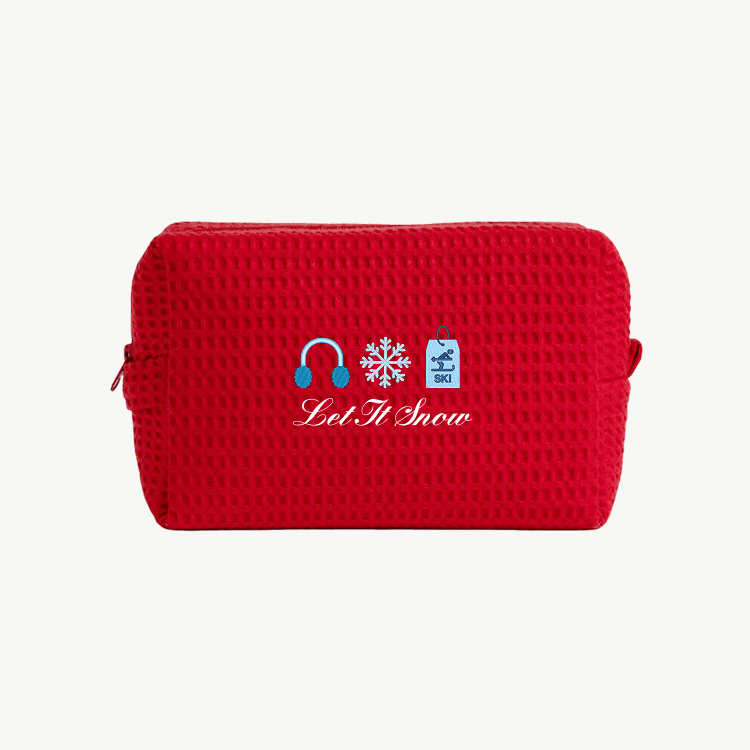 A red waffle pouch with embroidered images of an earmuff, a snowflake, and a ski sign, along with the words Let It Snow  beneath the images.