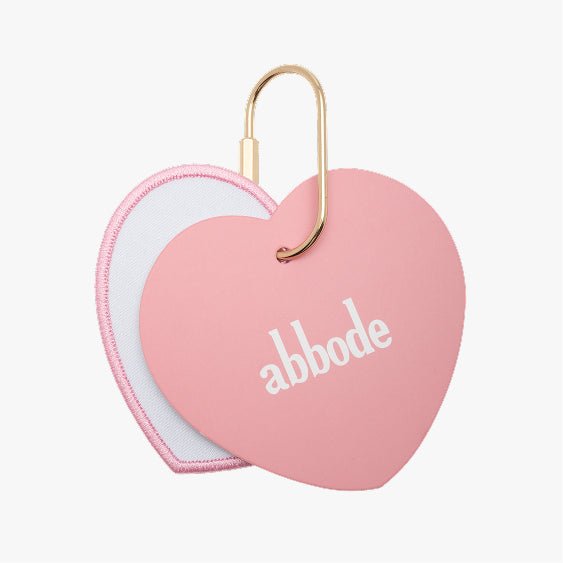 Heart charm keychain with a pink border and a white center and a pink oval charm. The pink heart charm has abbode written on the center The charm keychain has a gold key ring attached.
